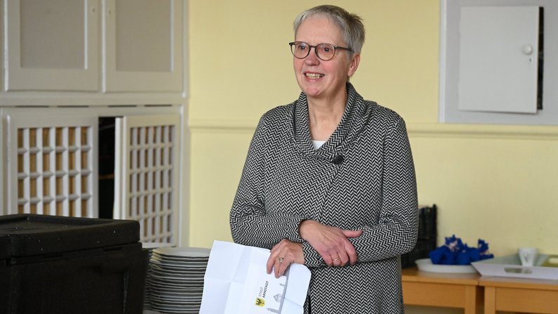 Auf dem Bild ist eine Frau zu sehen, die einen Briefumschlag in den Händen hält. 