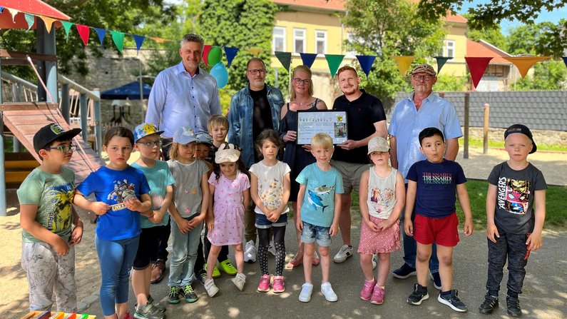 Auf dem Bild sind fünf Erwachsene sowie 11 Kinder zu sehen. Zwei Erwachsene haben eine Spendenurkunde in den Händen. 